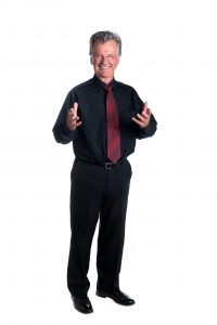 Garth Roberts, in shirt & red tie, standing